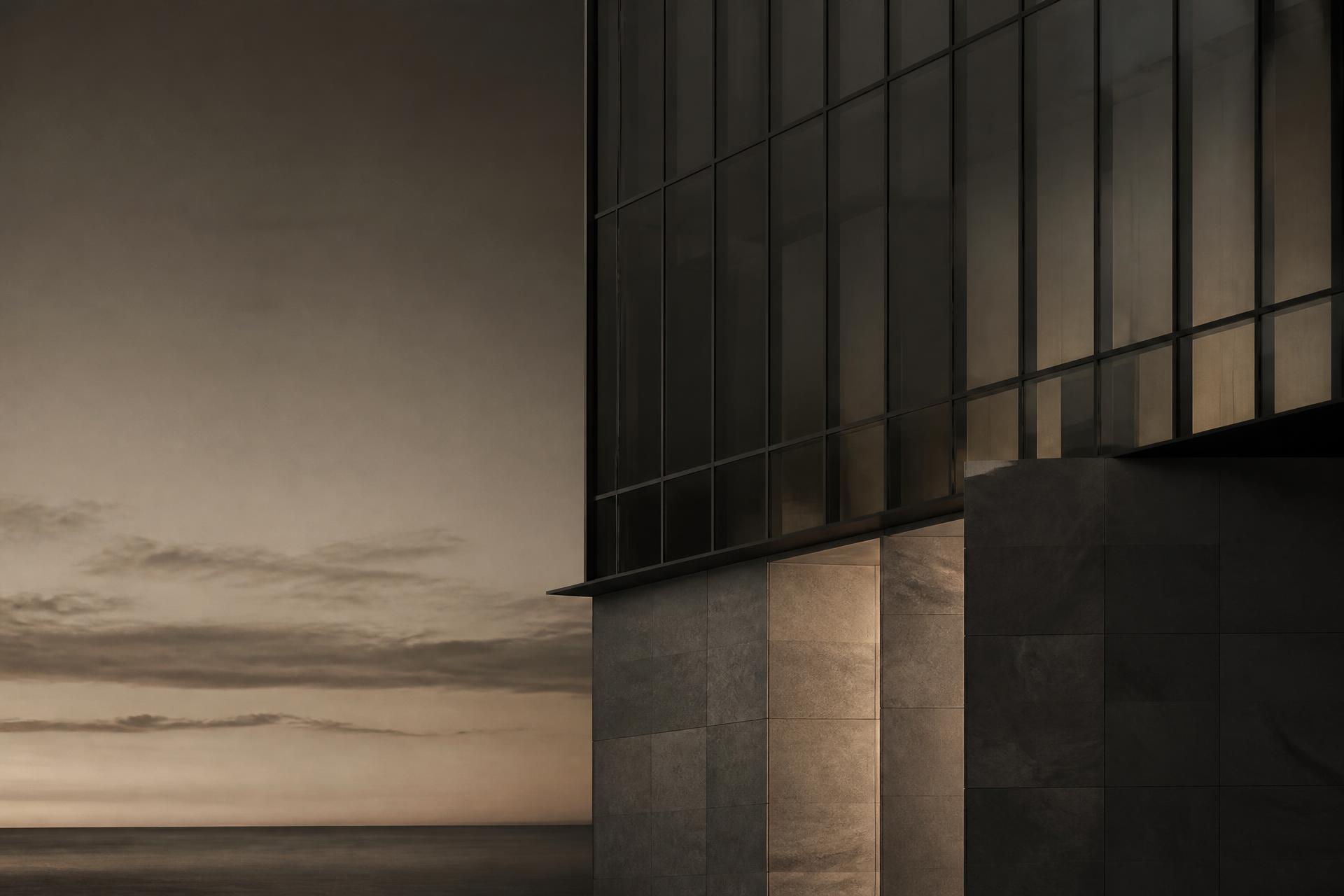 Stone and glass tower facade at dusk above an empty horizon